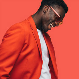 Man laughing and wearing an orange jacket on an orange background