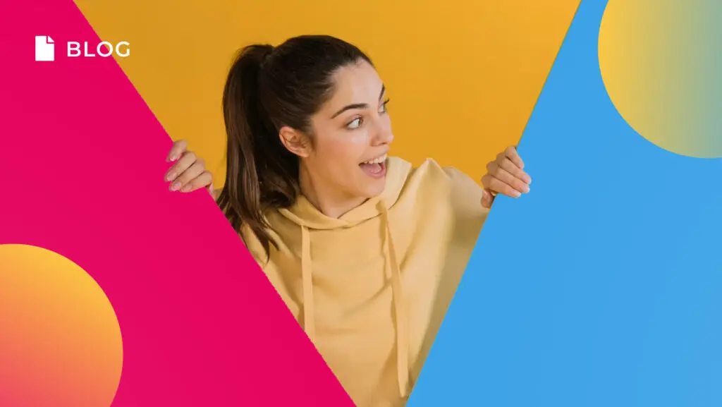 A woman in a yellow hoodie smiles excitedly, holding a triangular pink panel against a vibrant yellow and blue background with abstract shapes. The word 